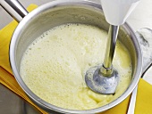 Mixing ingredients with hand blender in bowl for preparation of white butter sauce, step 4