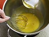 Close-up of oil being poured in mayonnaise and egg yolks mixture, step 3