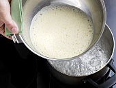 Close-up of hand holding mixture of champagne sabayon upon boiling water, step 3