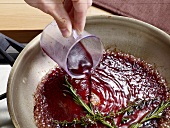 Close-up of red wine being poured on herbs in sauce pan, step 3