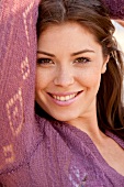 Portrait of pretty brunette woman with arm raised, smiling, close-up