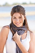 Portrait of beautiful brunette woman wearing white top and scarf, smiling