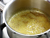 Close-up of boiling orange in sauce pan for preparation of orange sauce, step 1