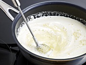 Close-up of mixture of milk, vanilla and butter being mixed with whisk, step 4