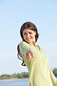 Portrait of happy woman wearing yellow top and pointing towards camera, smiling