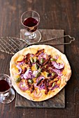 Tarte flambée with red onions, dried tomatoes and caper fruits
