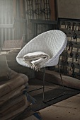 White wicker chair with shawl in room