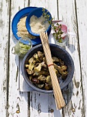 Porcini mushrooms in bowl with herb butter, skewers and bread crumbs on wood