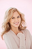 Portrait of beautiful blonde woman wearing pink sweater, smiling