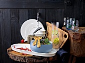 Bowl of vegetables, jug and glass on wooden block