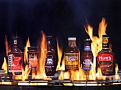 Various barbecue sauces on grill with flames