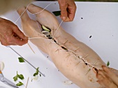 Close-up of stuffed suckling pig being tied