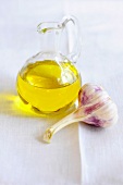 Olive oil in carafe beside garlic bulb