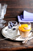 Poppy cream with blueberries and chocolate cream with orange sauce in bowls