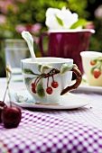 Porcelain cup with cherry pattern on saucer and spoon