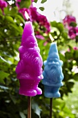 Close-up of pink and blue gnomes candles in garden