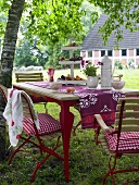 Garden table with red folding chairs with seat cushions and tablecloth
