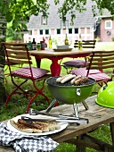Sausages on plate and kettle grill on bench