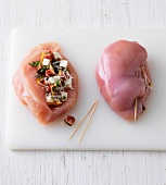 Chicken breast fillet with stuffing tied with toothpicks on chopping board
