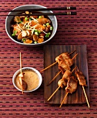 Chicken satay skewers on wooden board and yakitori sauce in bowl