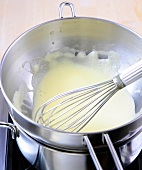 Close-up of whisked eggs with whisk in pan for preparation of hollandaise sauce, step 3
