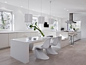 A spacious modern kitchen in white with a long dining and seating area
