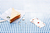 Sandwich and playing cards on blue checked blanket
