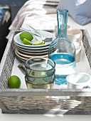 Stack of plates, glasses, goblet and decanter in wicker tray