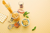 Spaghetti, macaroni, farfalle and sauce on beige background