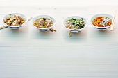 Four different soups of Asian noodle in bowls