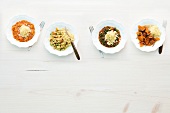 Four different dishes of couscous on plates with fork