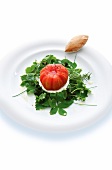 Skinned heirloom tomato on goat cheese and wild herbs salad on plate