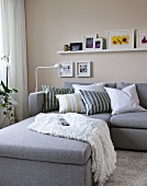 Living room with gray sofa, cushions and shelf board