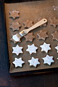 Cream on star shaped cookies in baking tray for preparation of Christmas cookies, step 3