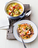 Cabbage stew with trout fillets on plate and shrimp in pot on wooden platter
