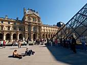 Tourists at Louvre pyramid facade in Paris, France