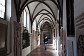 Woman walking in cloister at St. Anne's Church, Augsburg, Bavaria, Germany