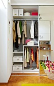 Clothes hanging in wardrobe shelves