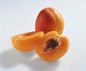 Whole and halves of apricots on white background