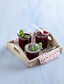 Pink grapefruit jelly in glass jars on wooden tray