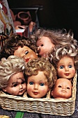 Diverse Puppenköpfe alter Puppen in einem Korb