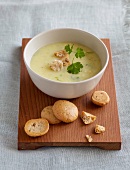 Parsnip soup in bowl with shaking bread on wooden board