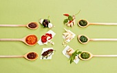 Various ingredients of pesto in wooden spoons