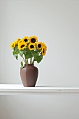 Vase with sunflowers on white table