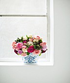 Bouquet of garden roses in vase on window sill