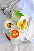 Different types of ice cold soups in glasses on serving plate, low GI diet food