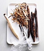 Purple salsify and peeled purple salsify with peeler on tray, step 1