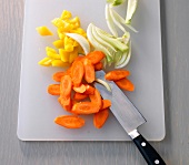 Slices of carrot and cabbage with knife on chopping board