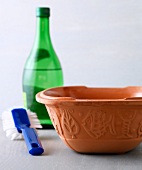 Earthenware serving dish with brush and bottle