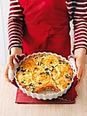 Close-up of woman holding casserole with spaghetti with veal
